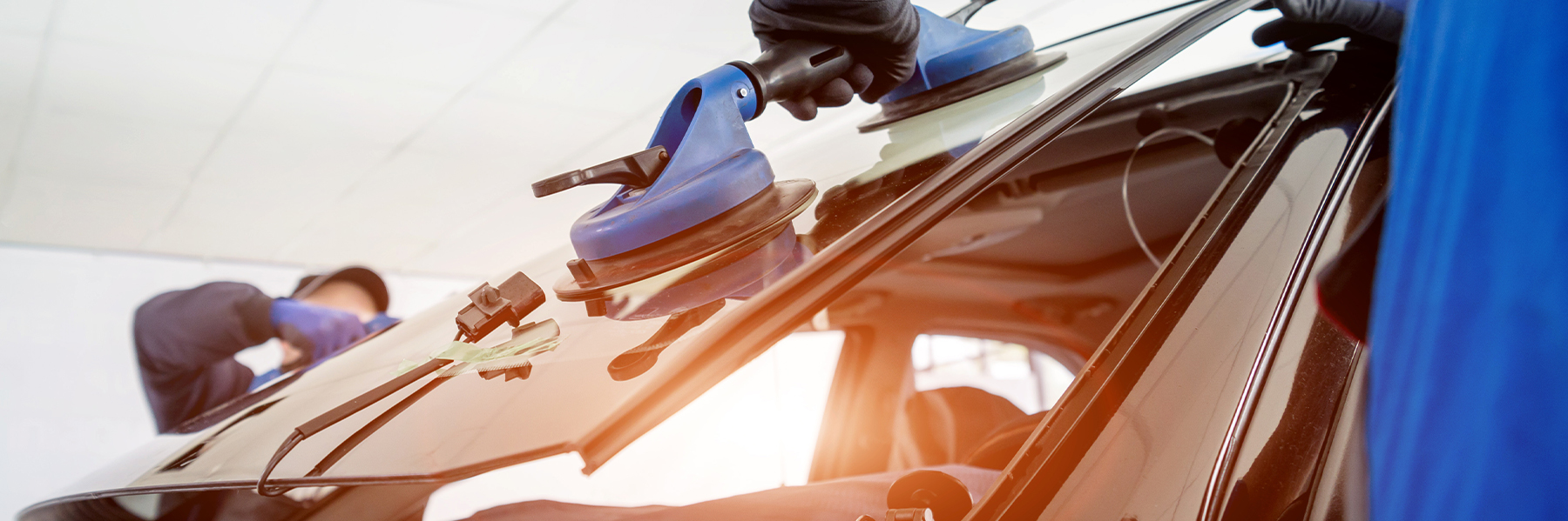 Autoglaser ersetzen Windschutzscheibe eines Autos in der Autowerkstatt. Autoglaser ersetzen Windschutzscheibe eines Autos in der Autowerkstatt.