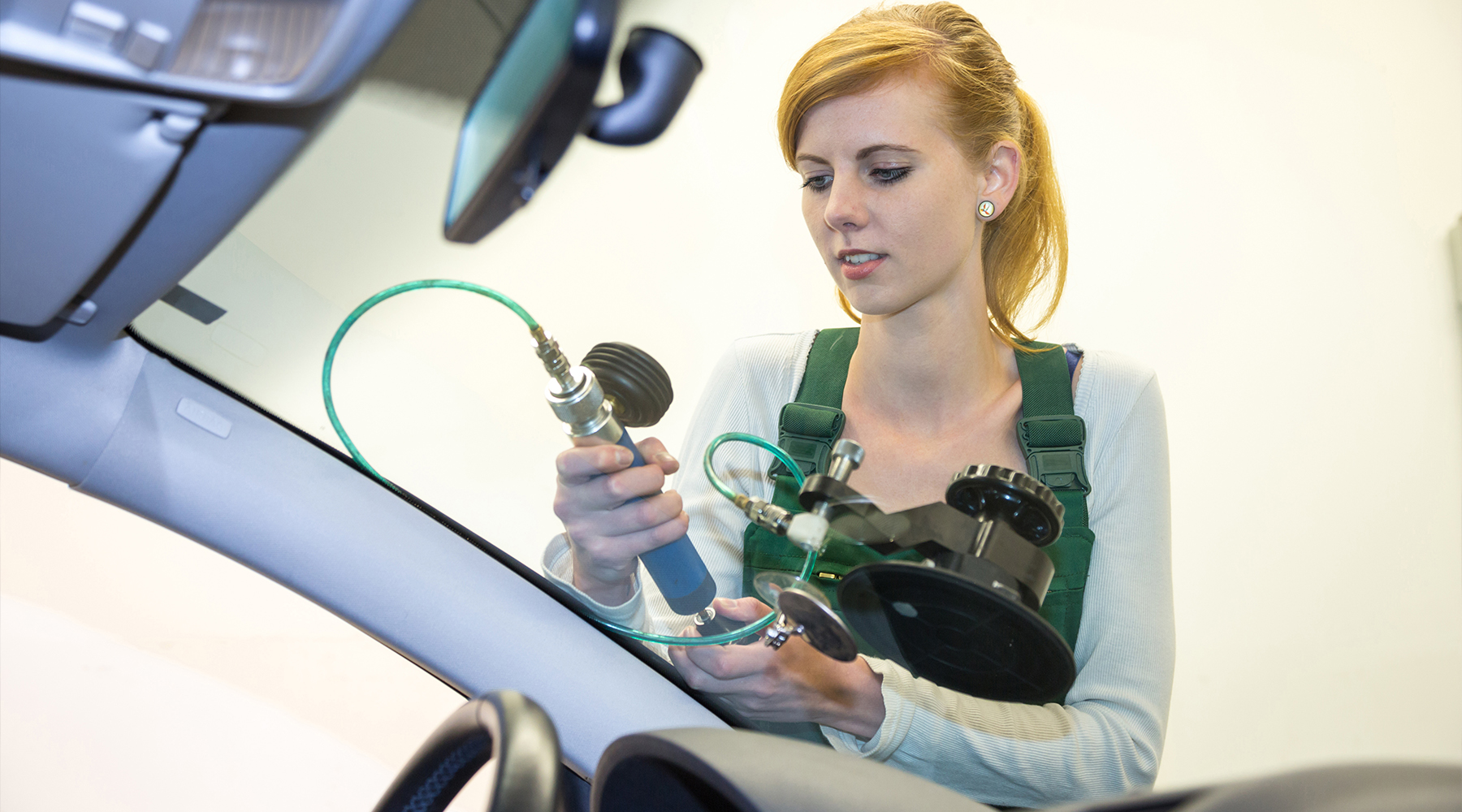 Autoglaserin-Weiterbildung Autoglaserin mit einem Messgerät an einer Frontscheibe