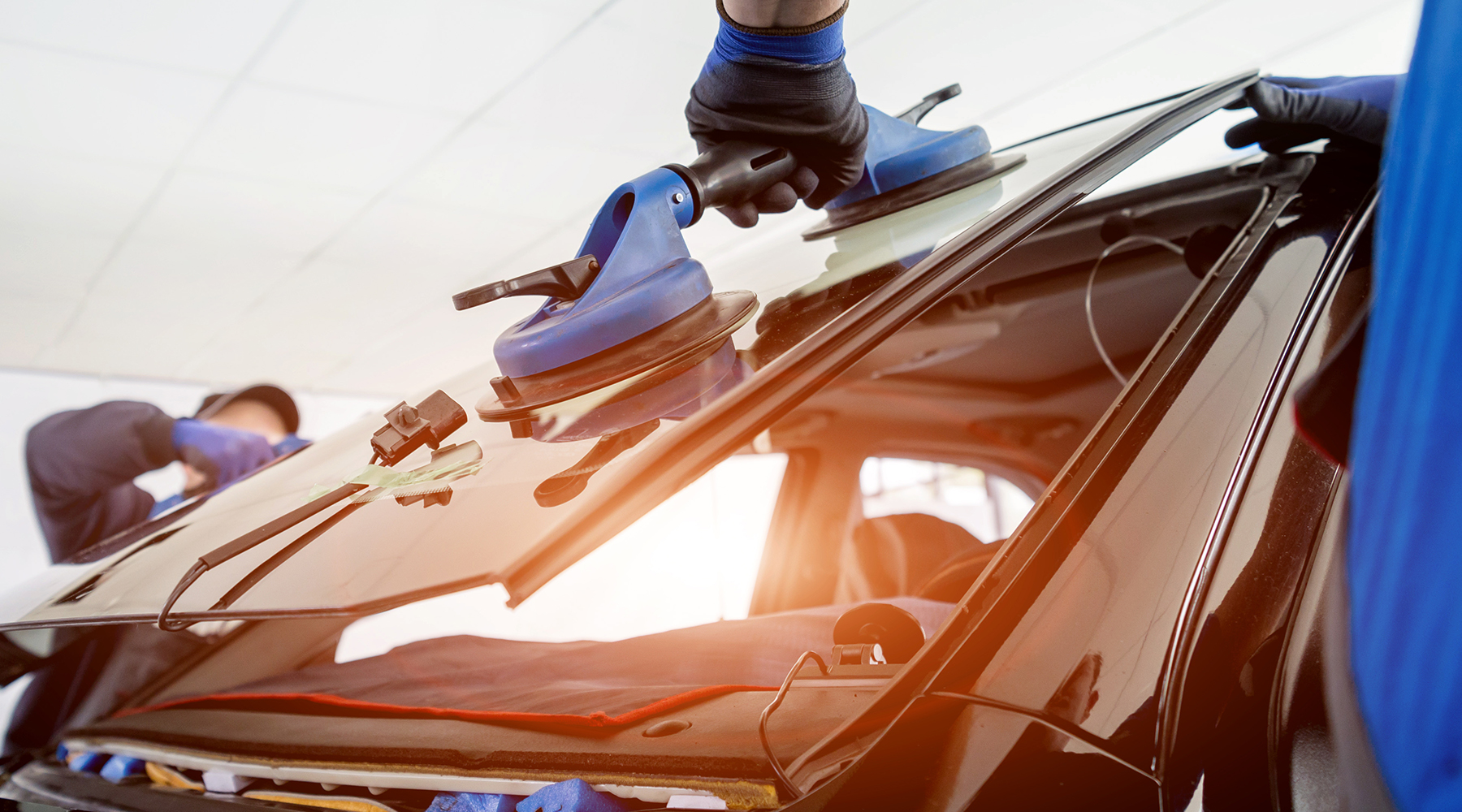 Autoglaser ersetzen Windschutzscheibe eines Autos in der Autowerkstatt.