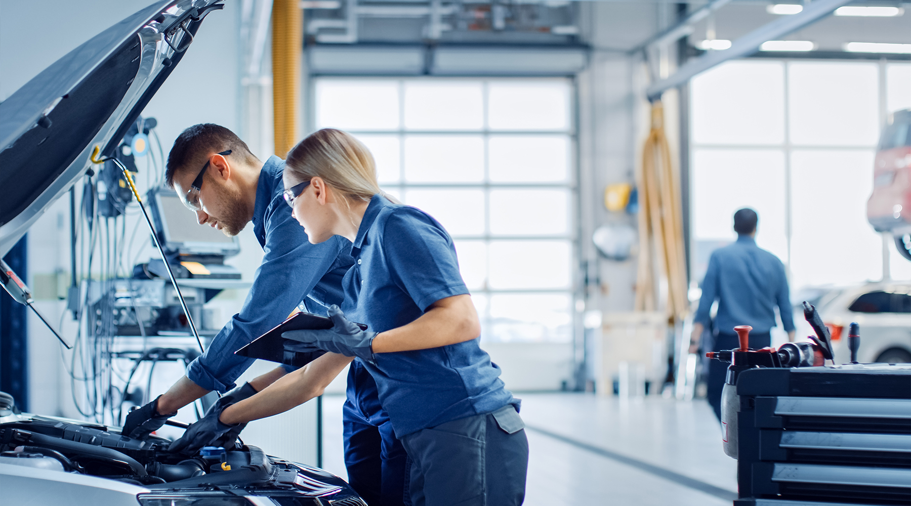 Zwei Diagnosetechniker in einem Service inspizieren ein Auto, nachdem sie die Diagnoseergebnisse erhalten haben. Diagnosetechniker nehmen Messungen an einem Fahrzeug mit offener Motorhaube vor.