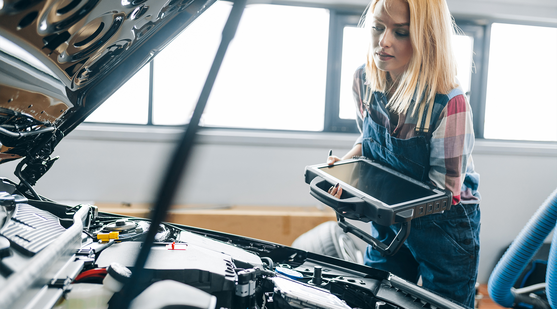 Eine Diagnosetechnikerin in einem Kfz-Servicebetrieb inspizieren ein Auto, nachdem sie die Diagnoseergebnisse erhalten hat. Eine Diagnosetechnikerin in einem Kfz-Servicebetrieb inspizieren ein Auto, nachdem sie die Diagnoseergebnisse erhalten hat.
