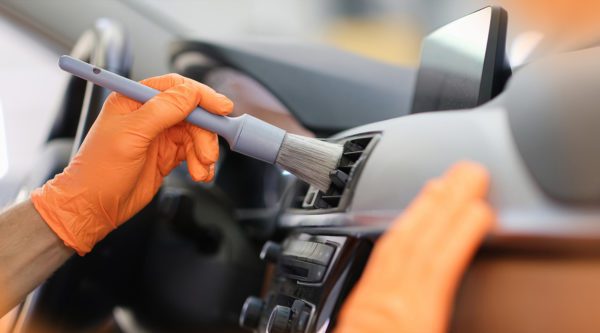 Männliche Hand hält graues Rouge in orangefarbenen Schutzhandschuhen
