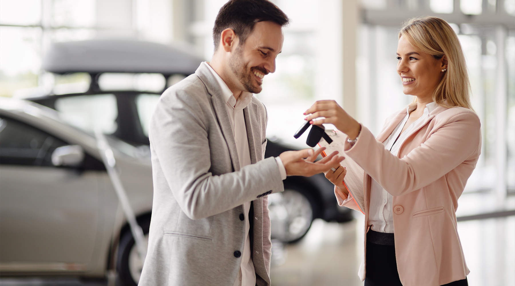 Flottenmanagerin im Autohaus Flottenmanagerin im Autohaus übergibt Autoschlüssel einem Kunden