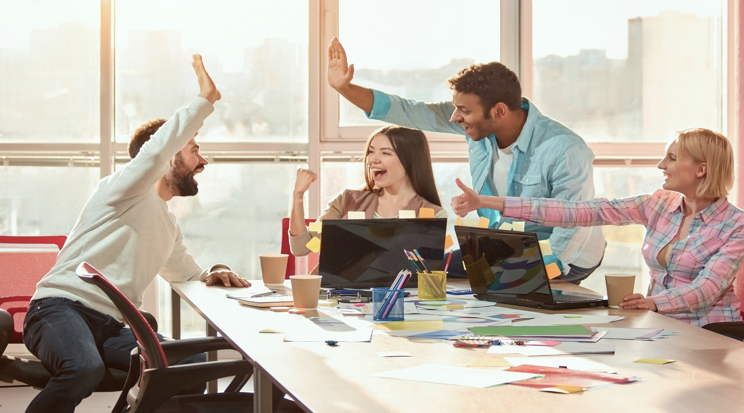 Vier Arbeitskollegen, die sich im Büro über die geleistete Arbeit freuen. Vier Arbeitskollegen, die sich im Büro über die geleistete Arbeit freuen.