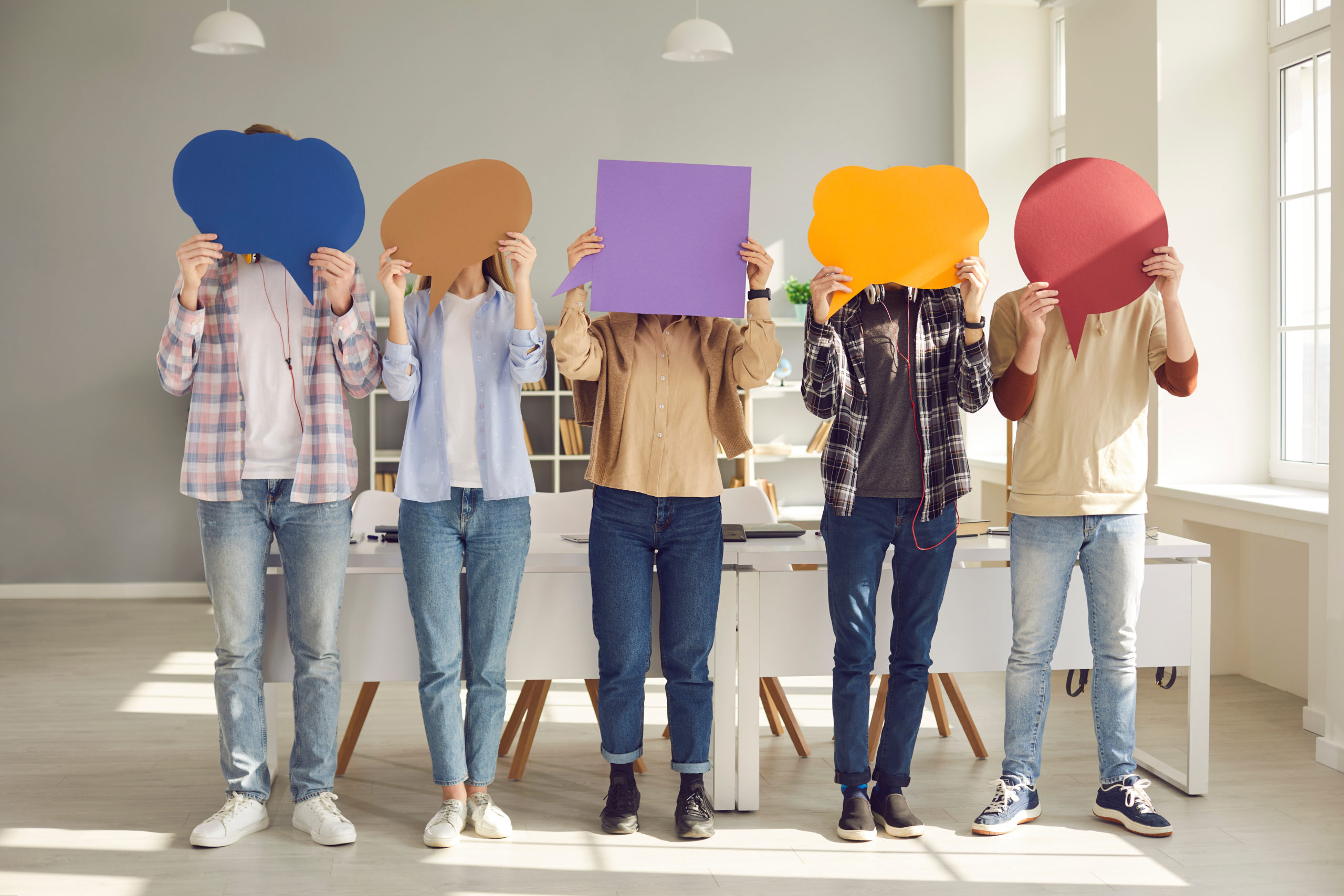 Group of college students covering faces with colorful paper mockup speech bubbles